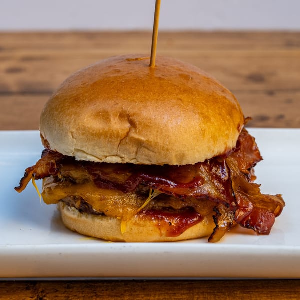 A Burger U bacon cheeseburger with melted cheese and barbecue sauce on a white plate.